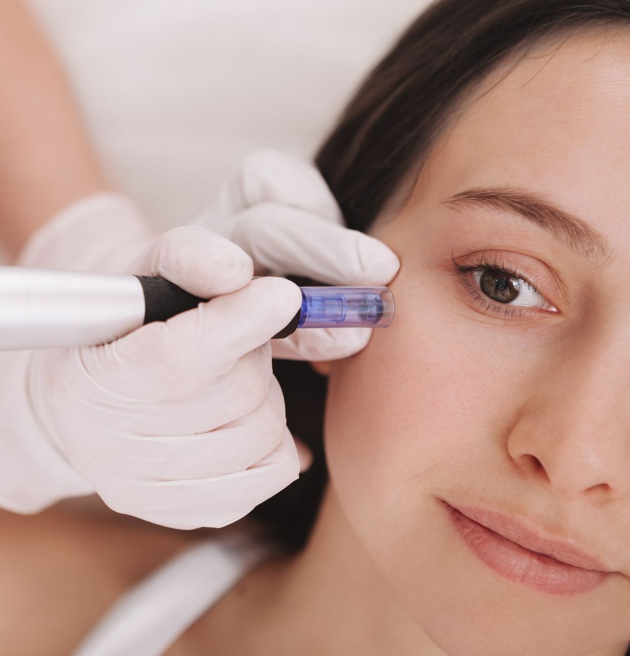 A smiling woman is applying lotion to her face.
