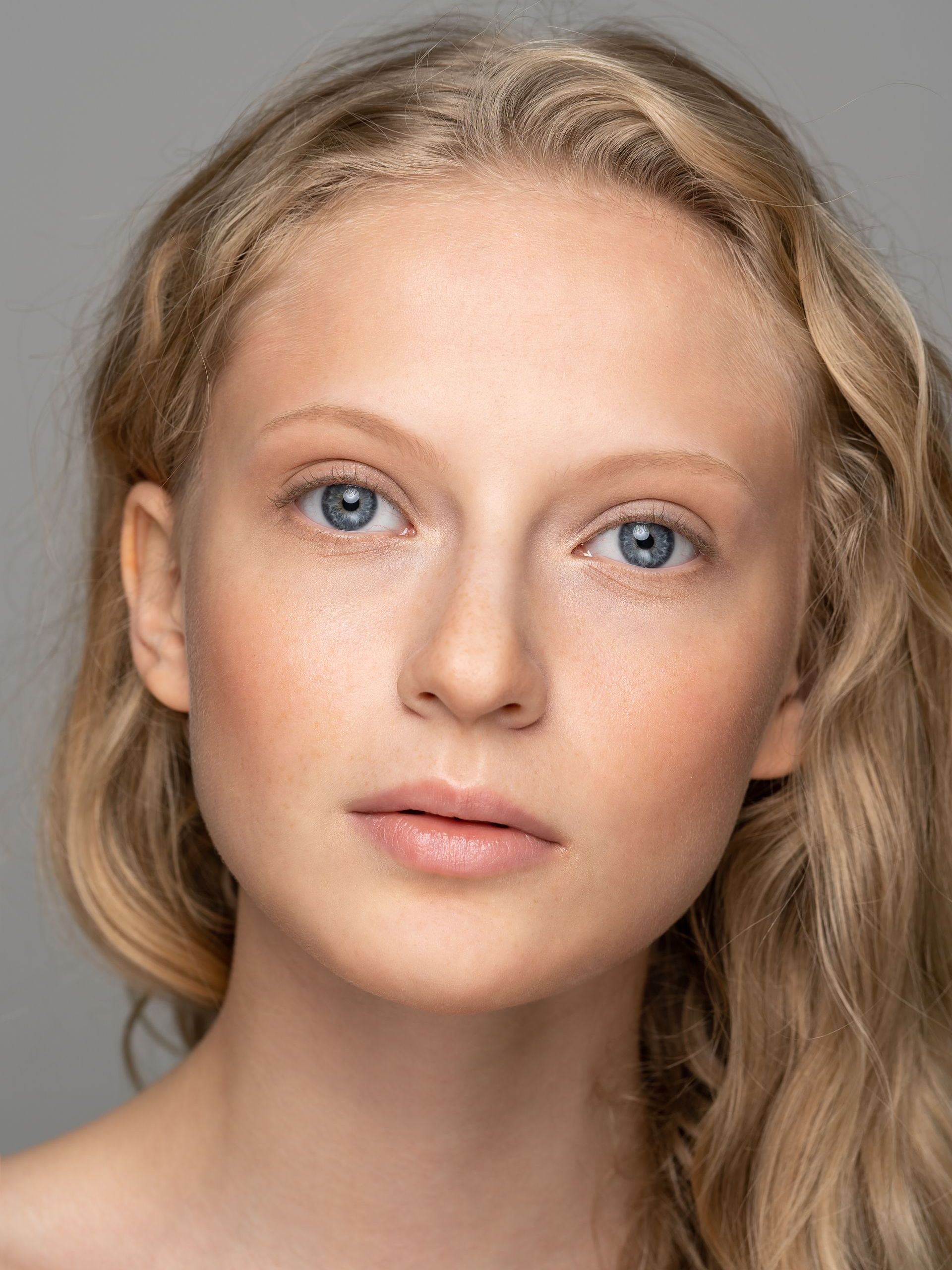 A close up of a woman 's face with blonde hair and blue eyes.