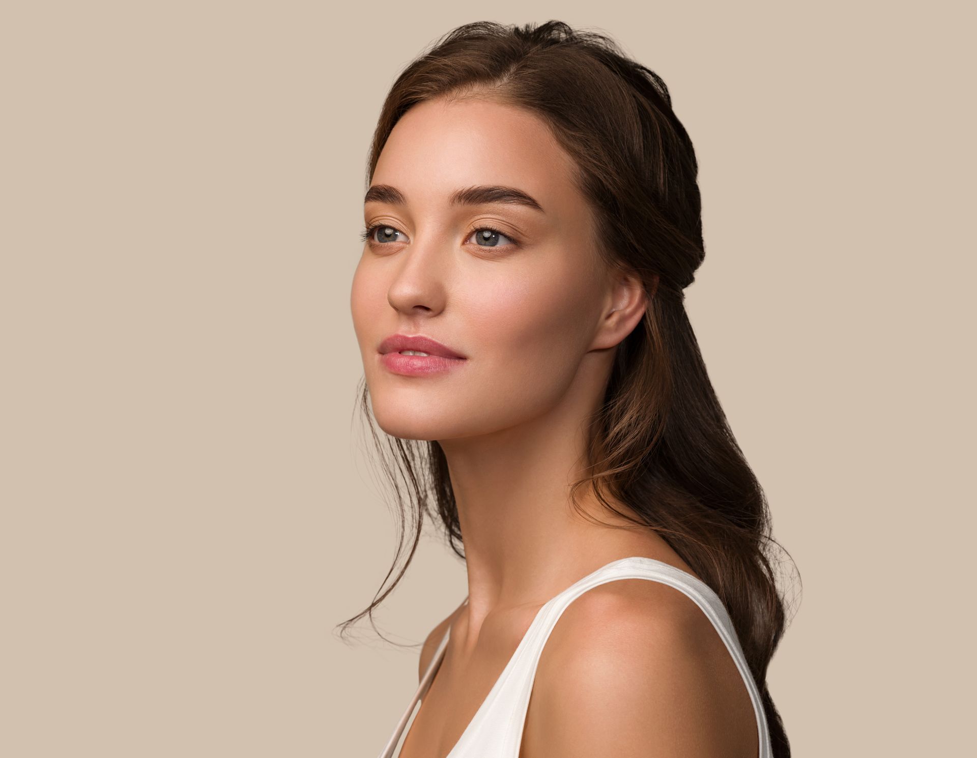 A woman in a white tank top is looking to the side.