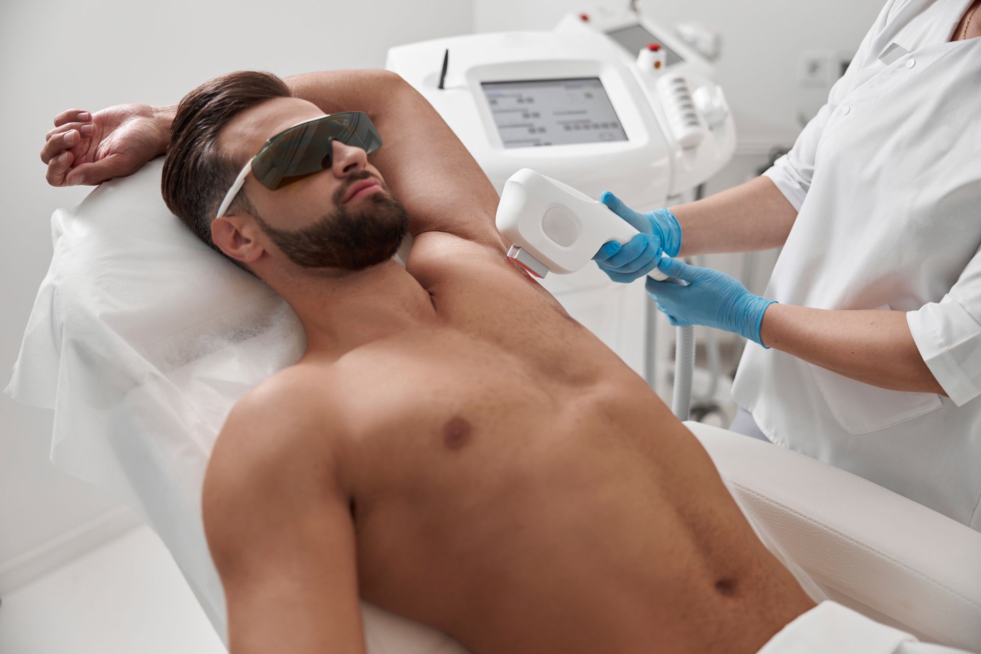 A man is getting a laser hair removal treatment on his armpits.