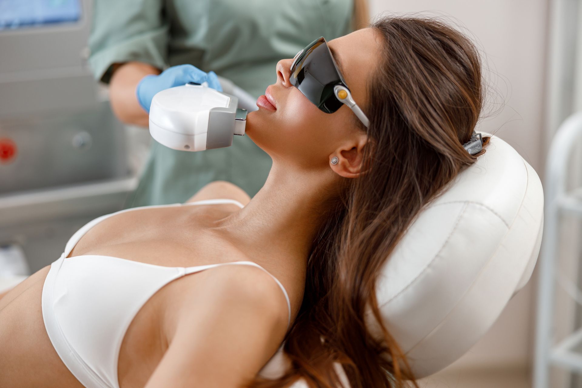 A woman is getting a laser hair removal treatment on her face.