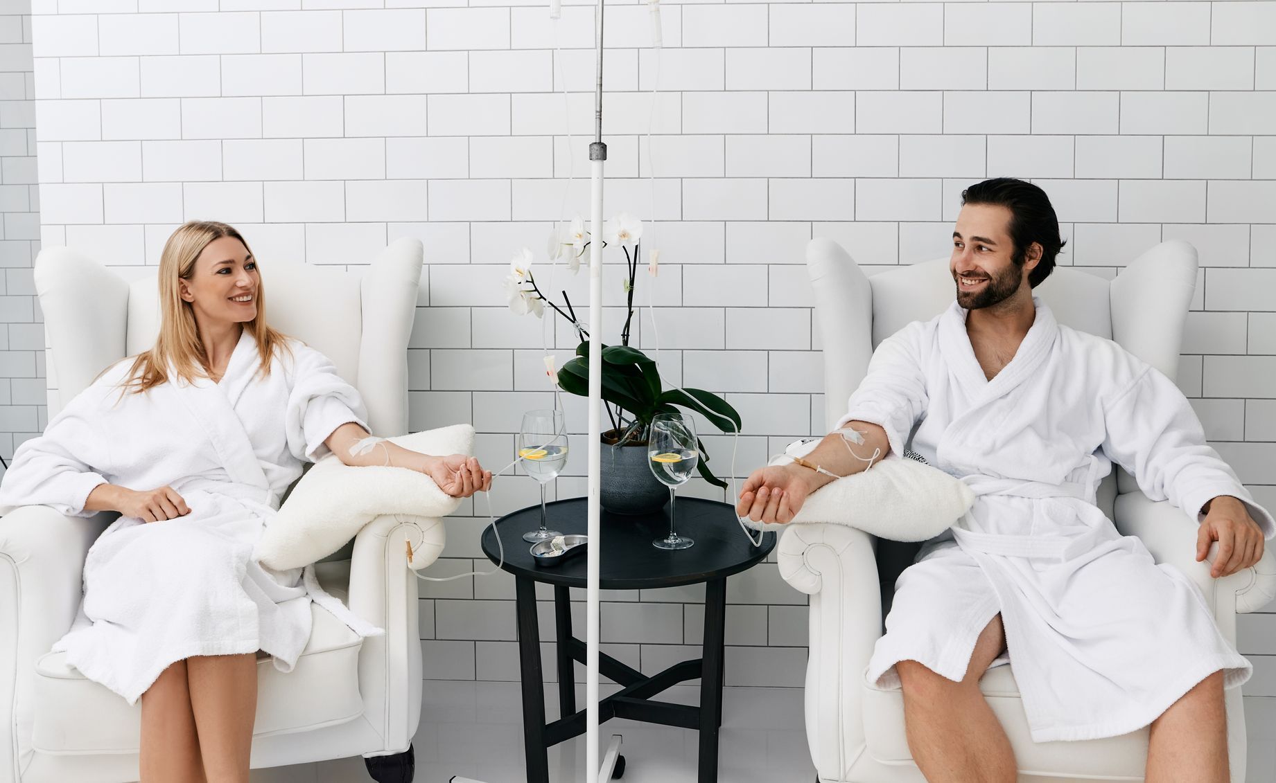 A man and a woman in bathrobes are sitting in chairs.