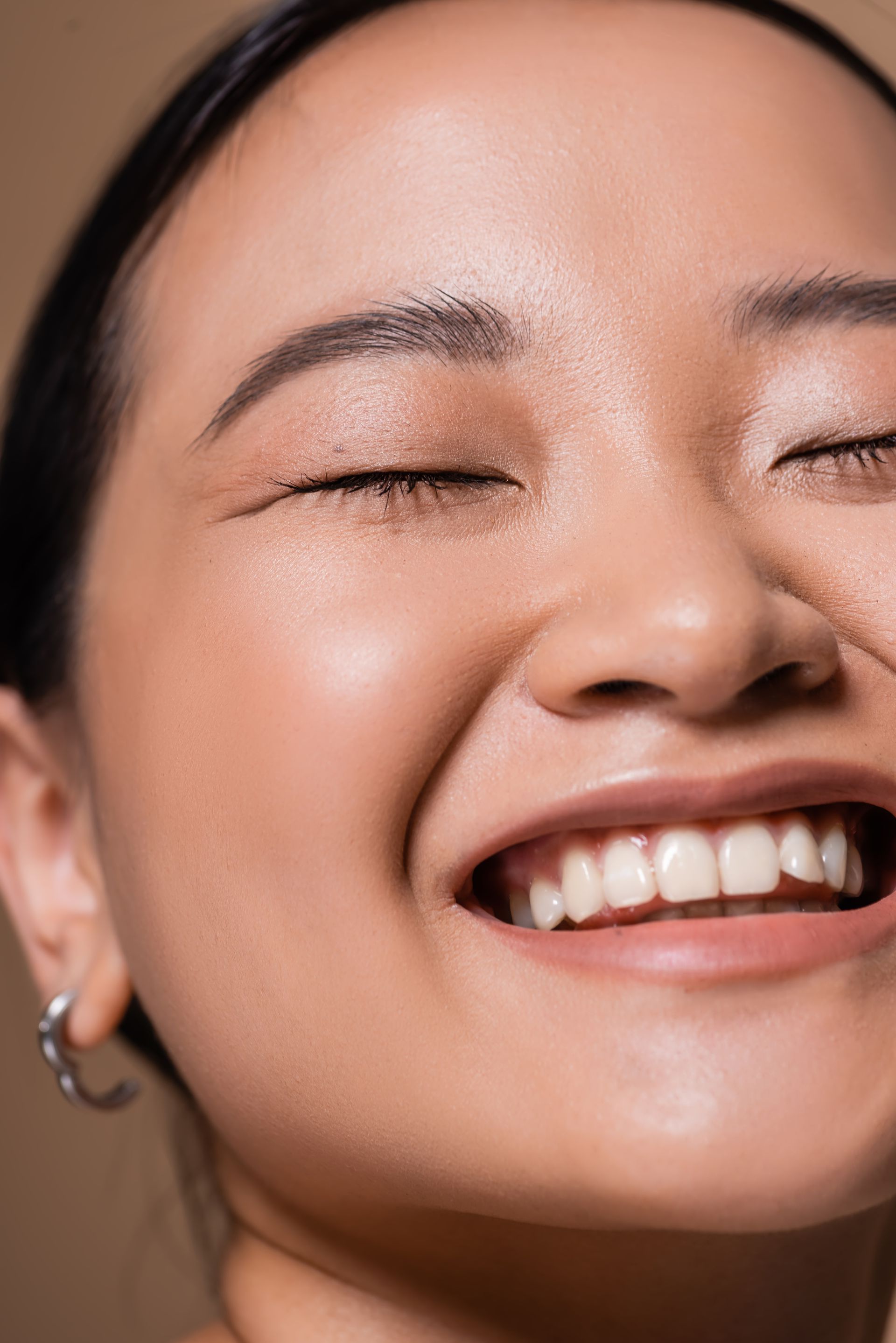 A close up of a woman 's face smiling with her eyes closed.