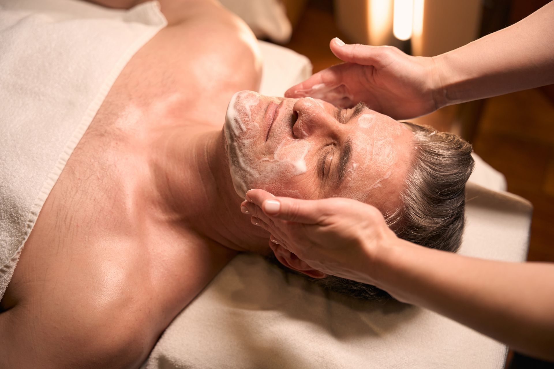 A man is getting a facial treatment at a spa.