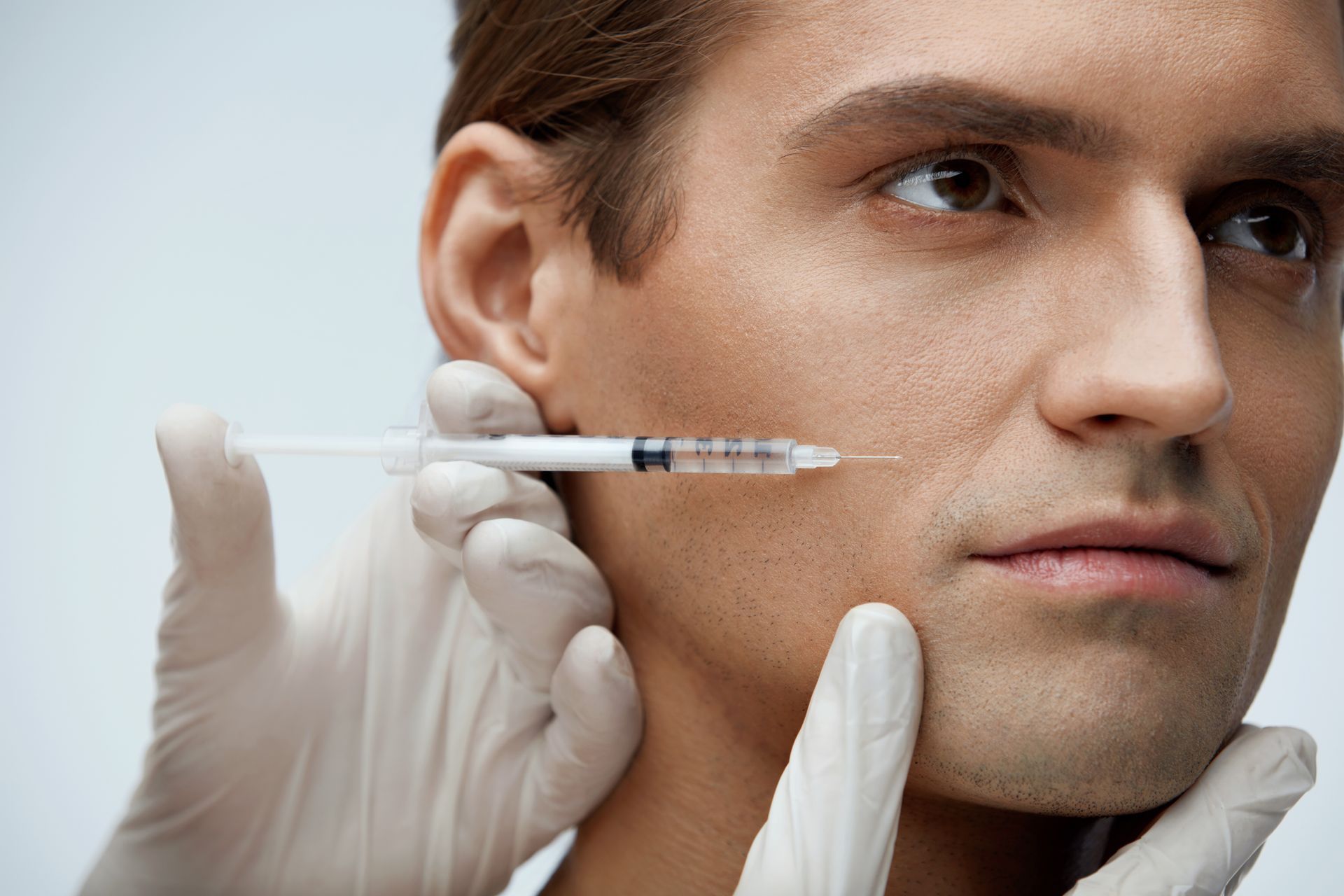 A man is getting a botox injection in his face.