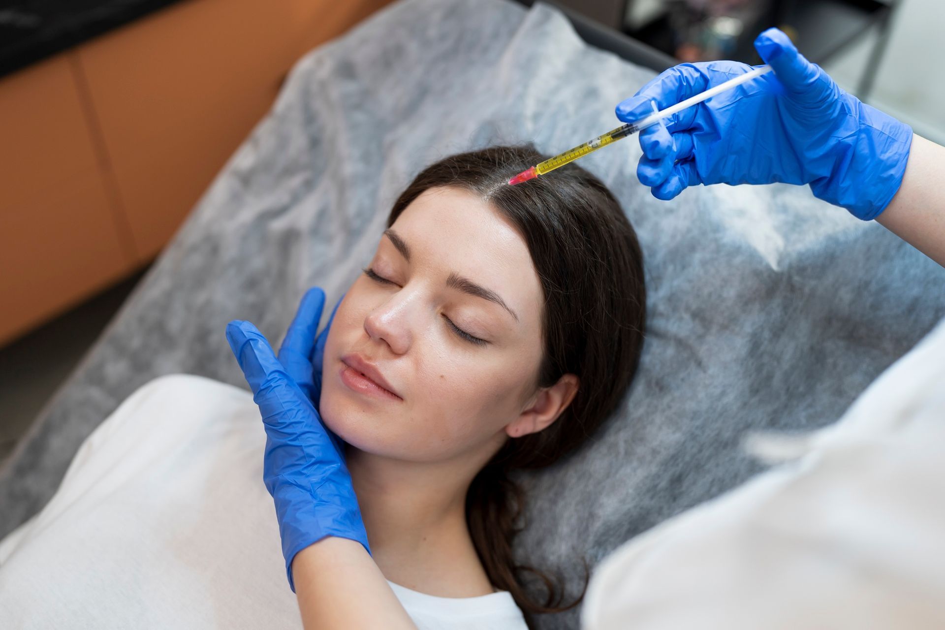 A woman is getting an injection in her head in a beauty salon.
