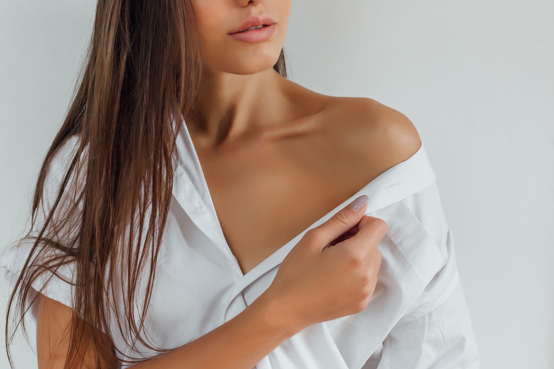 A woman in a white shirt is taking off her shirt.