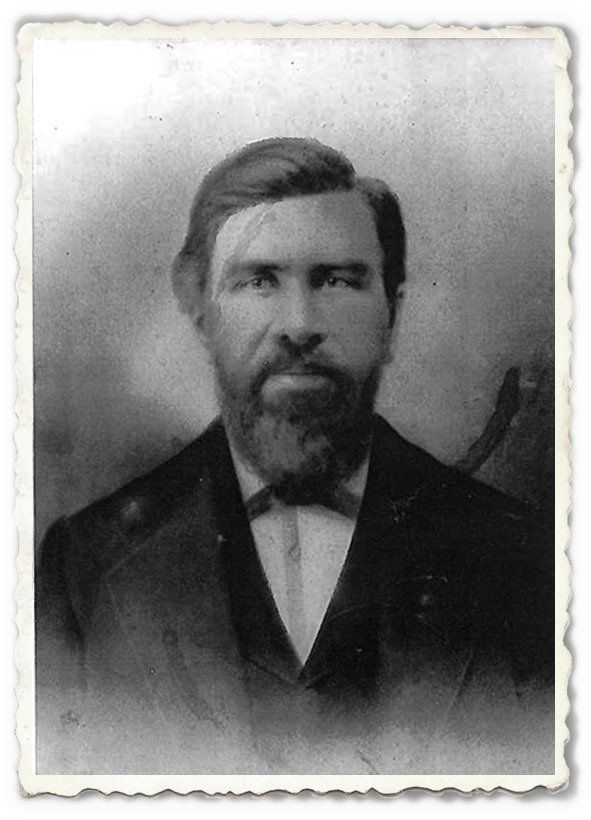 A black and white photo of a man with a beard wearing a suit and bow tie.