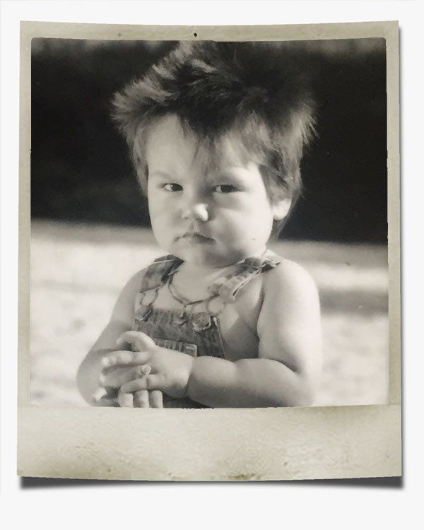 A black and white photo of a baby wearing overalls