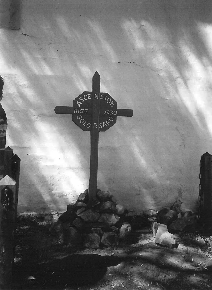 A black and white photo of a cross in a cemetery
