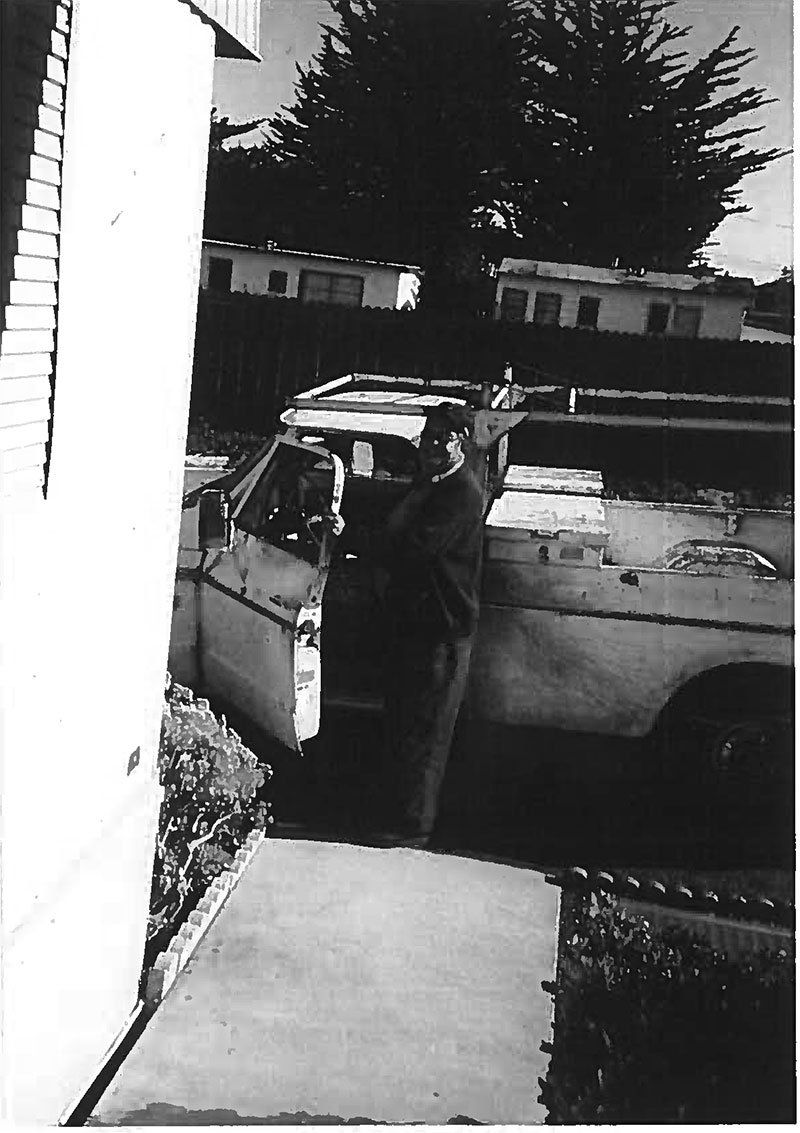 A black and white photo of a man getting out of a car