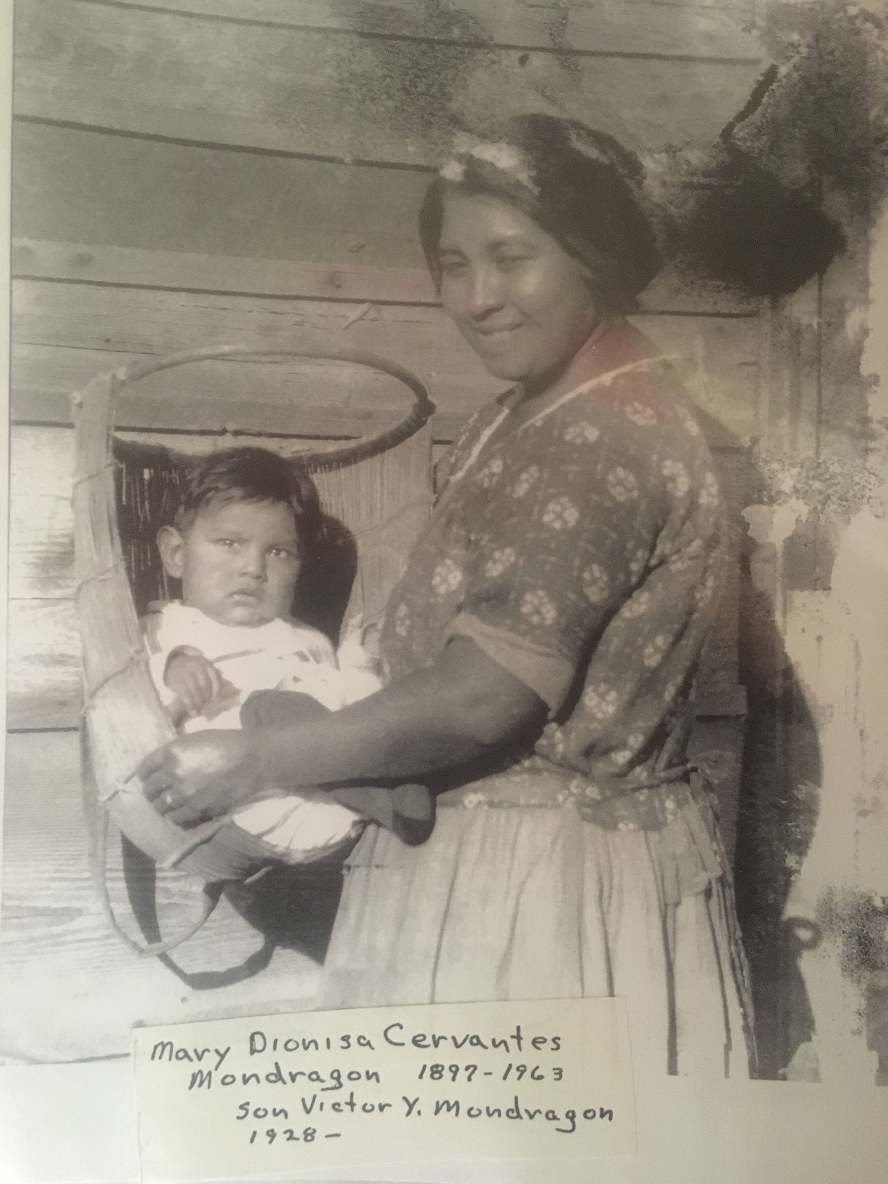 A black and white photo of a woman holding a baby in a stroller.