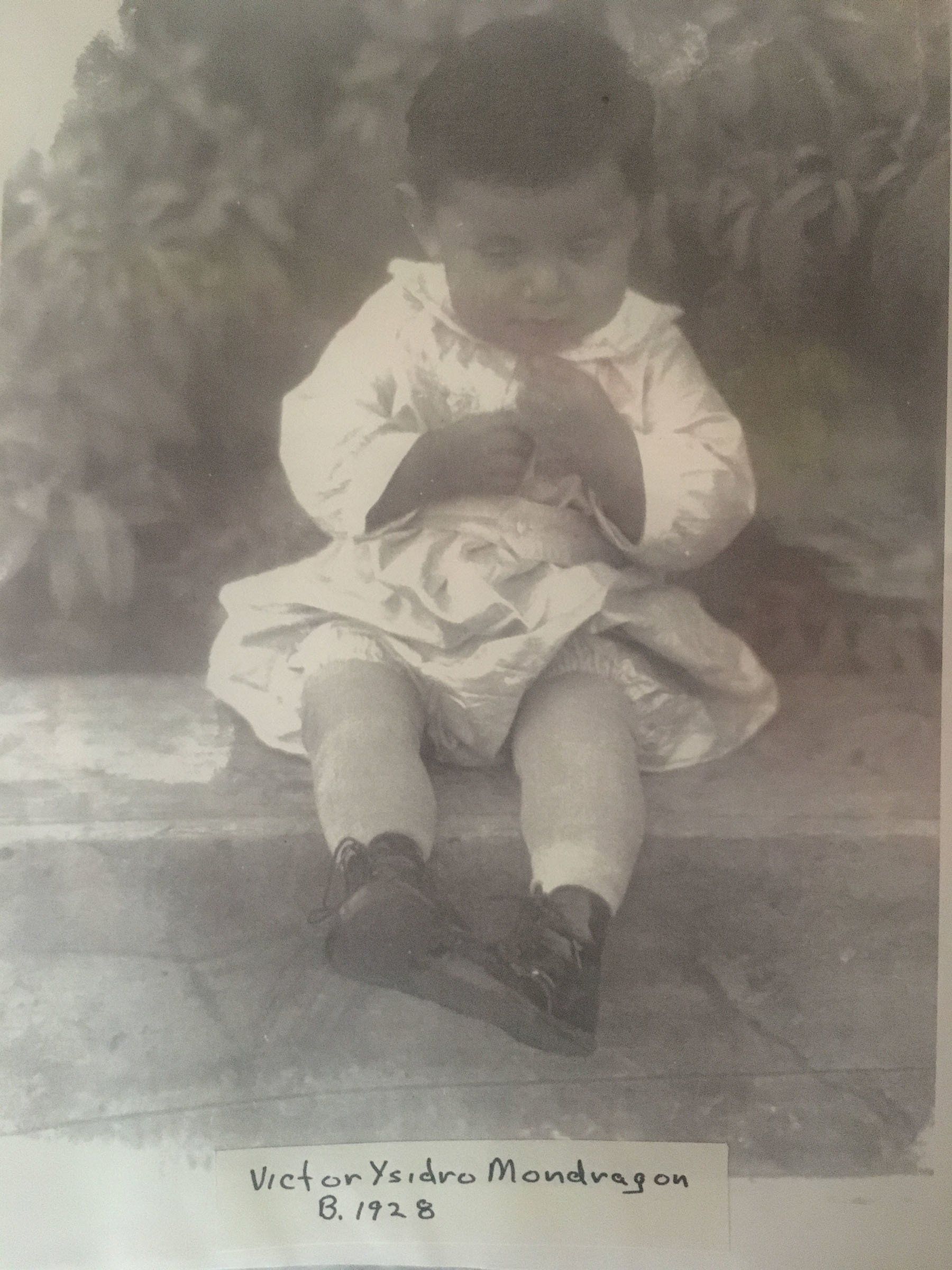 A black and white photo of a little boy sitting on a bench