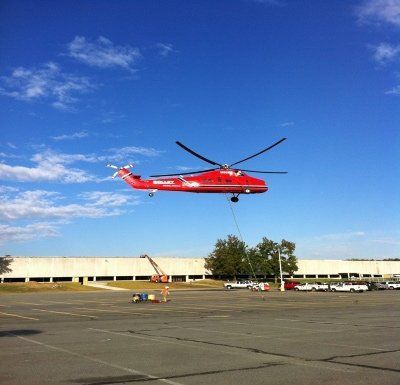 Red helicopter hovering over ground — Little Rock, AR — BM Mechanical Corp. Inc.