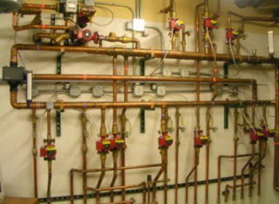Bronze pipes on white wall — Little Rock, AR — BM Mechanical Corp. Inc.