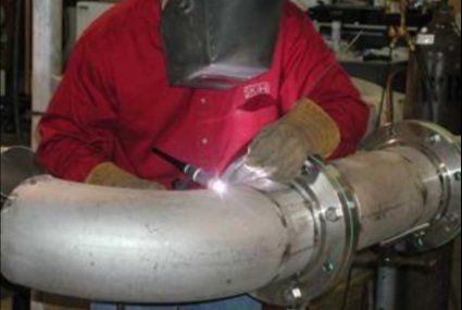 Man in red jumpsuit welding a pipe — Little Rock, AR — BM Mechanical Corp. Inc.