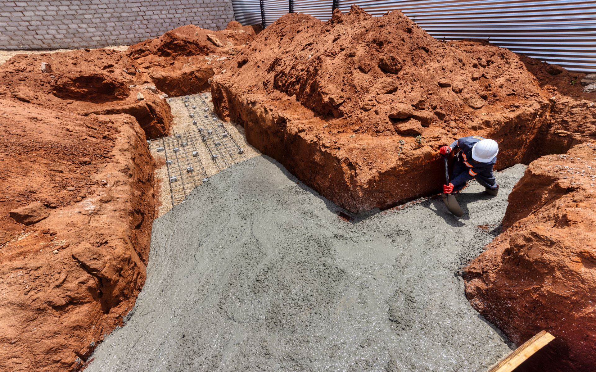 A man wearing a hard hat is working on a pile of dirt.