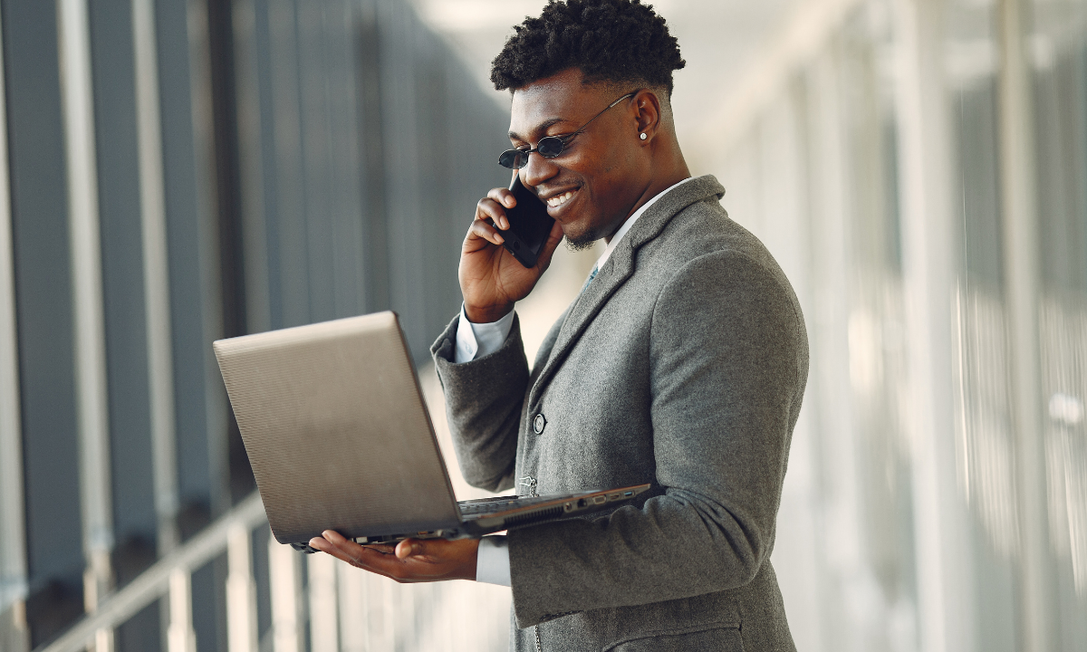 salesman-talking-on-phone-with-laptop-in-hand