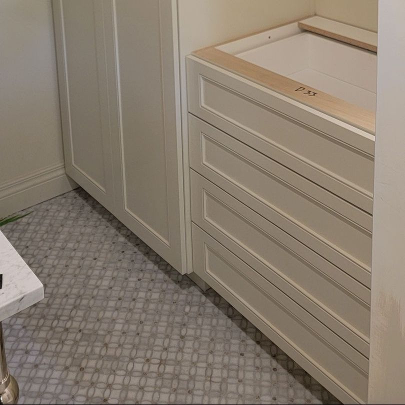 A bathroom with white cabinets and a marble counter top