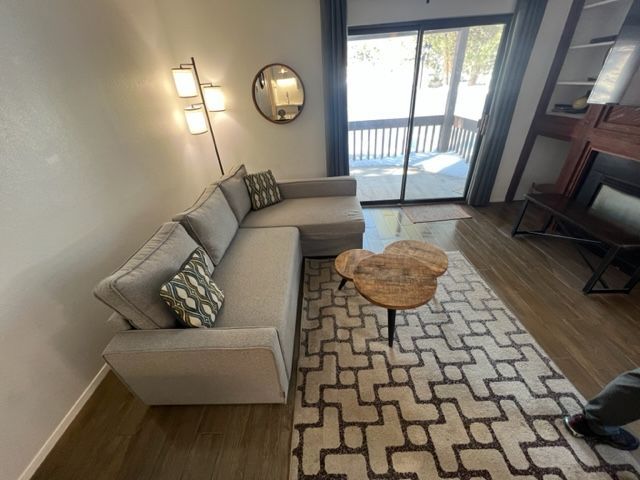 Living room with a gray sectional sofa, patterned rug, and wooden coffee table.  Snowy deck visible.