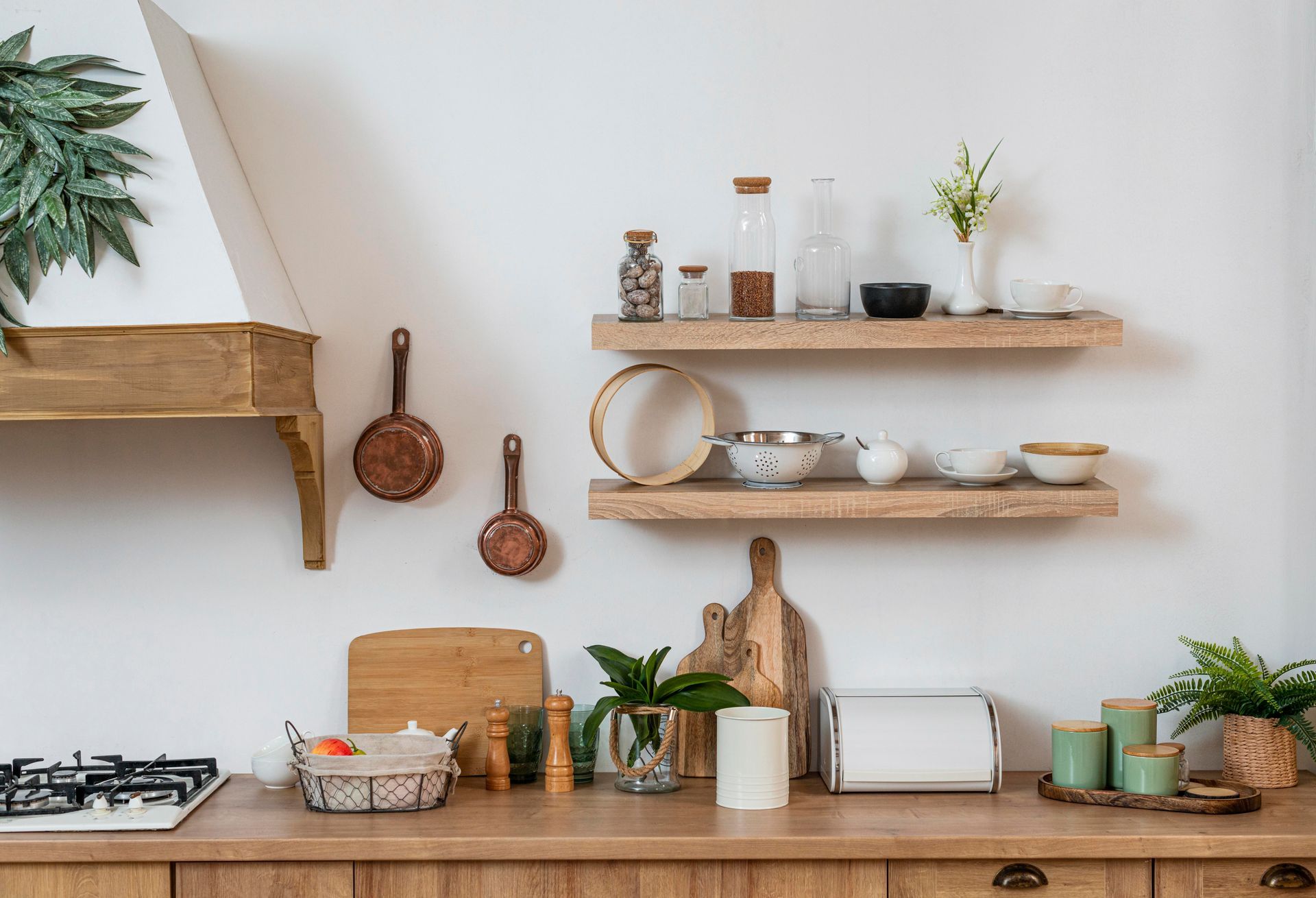 A kitchen with wooden cabinets , shelves , pots and pans , and a stove.