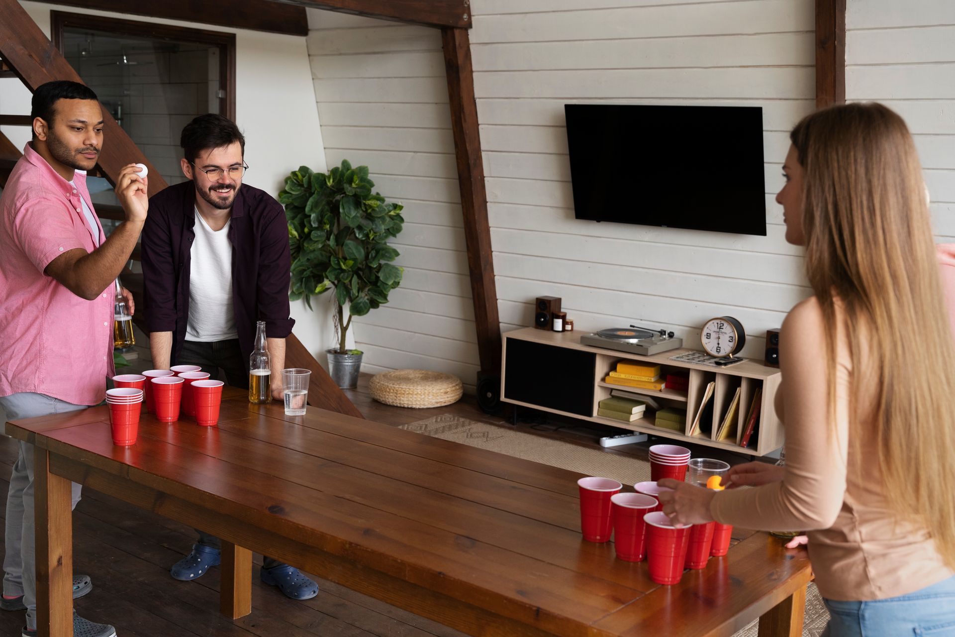 A group of people are playing beer pong in a living room.