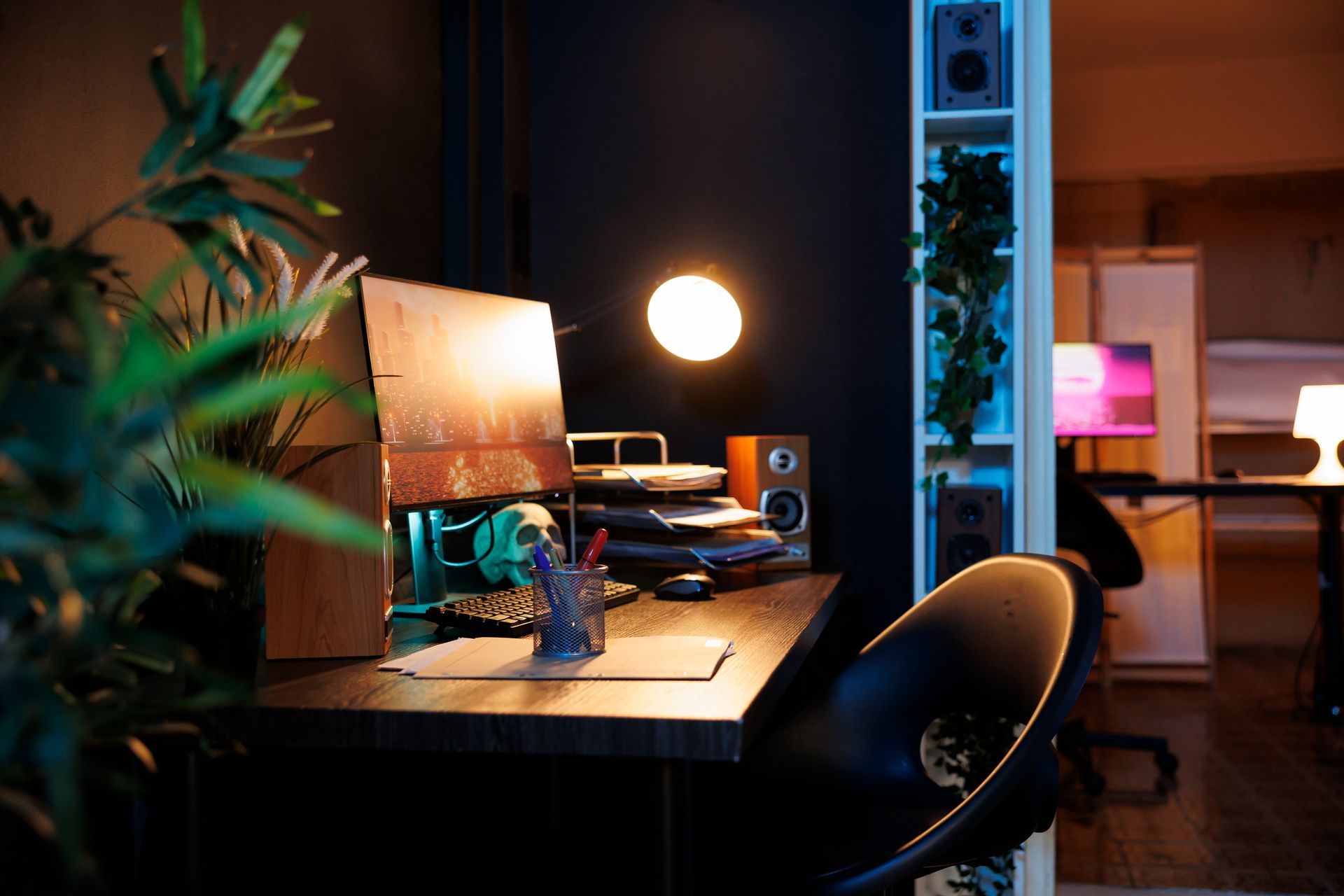A desk with a computer on it in a dark room.