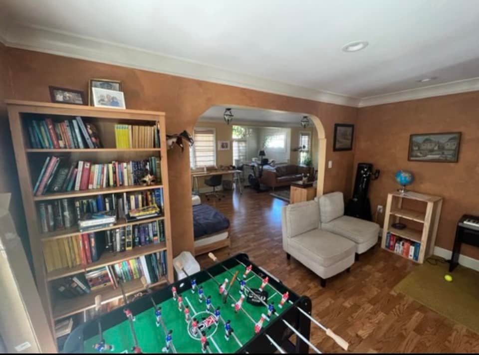 Living room with foosball table, bookshelf, couch, and archway leading to another room.