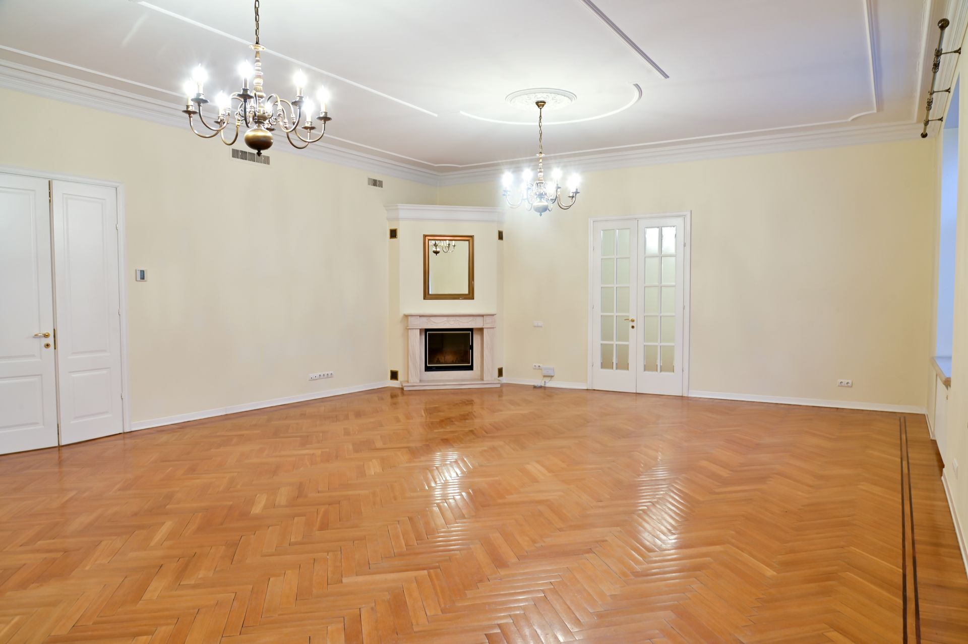 A large empty room with a wooden floor and a fireplace.