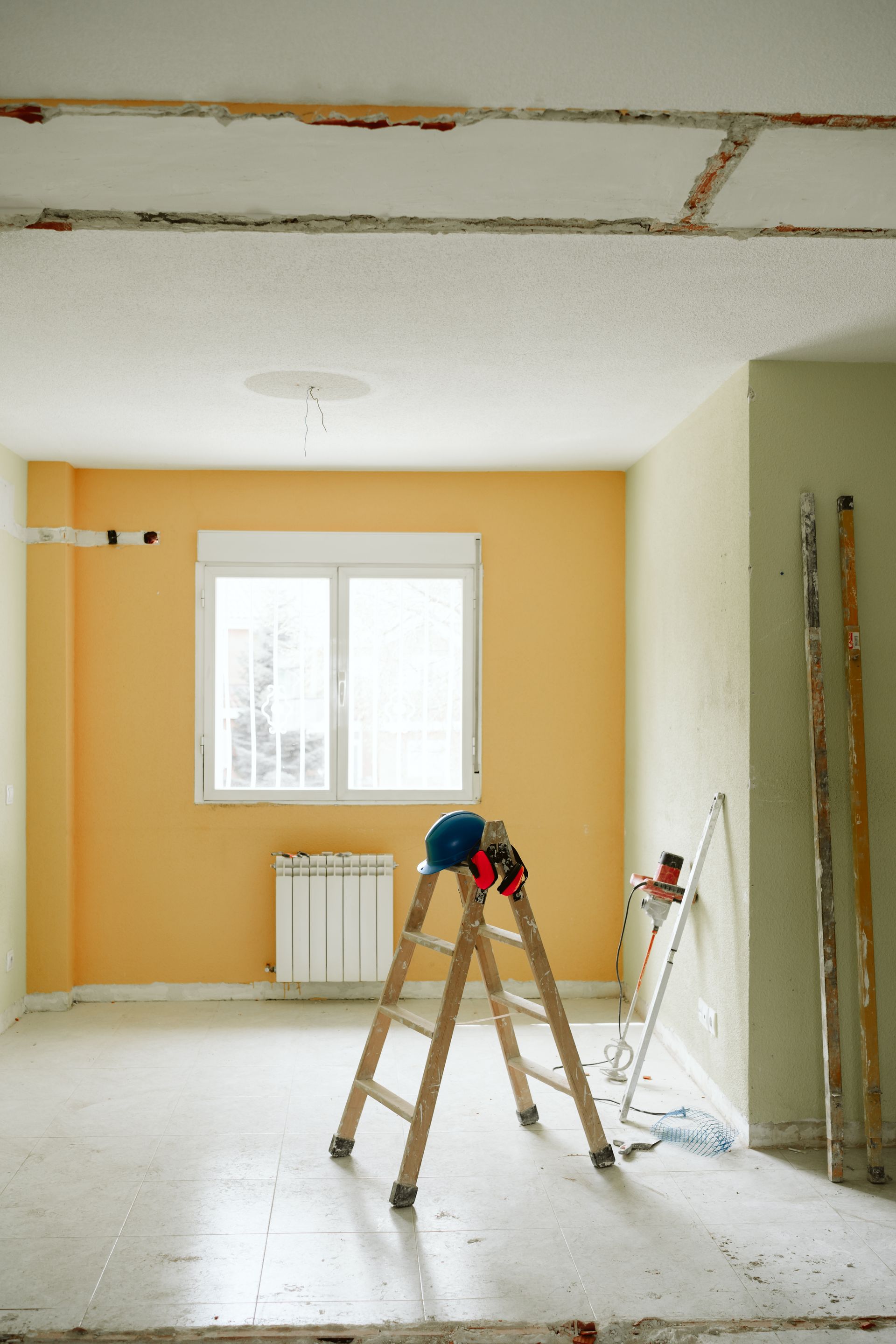 A wooden ladder is sitting in the middle of an empty room.