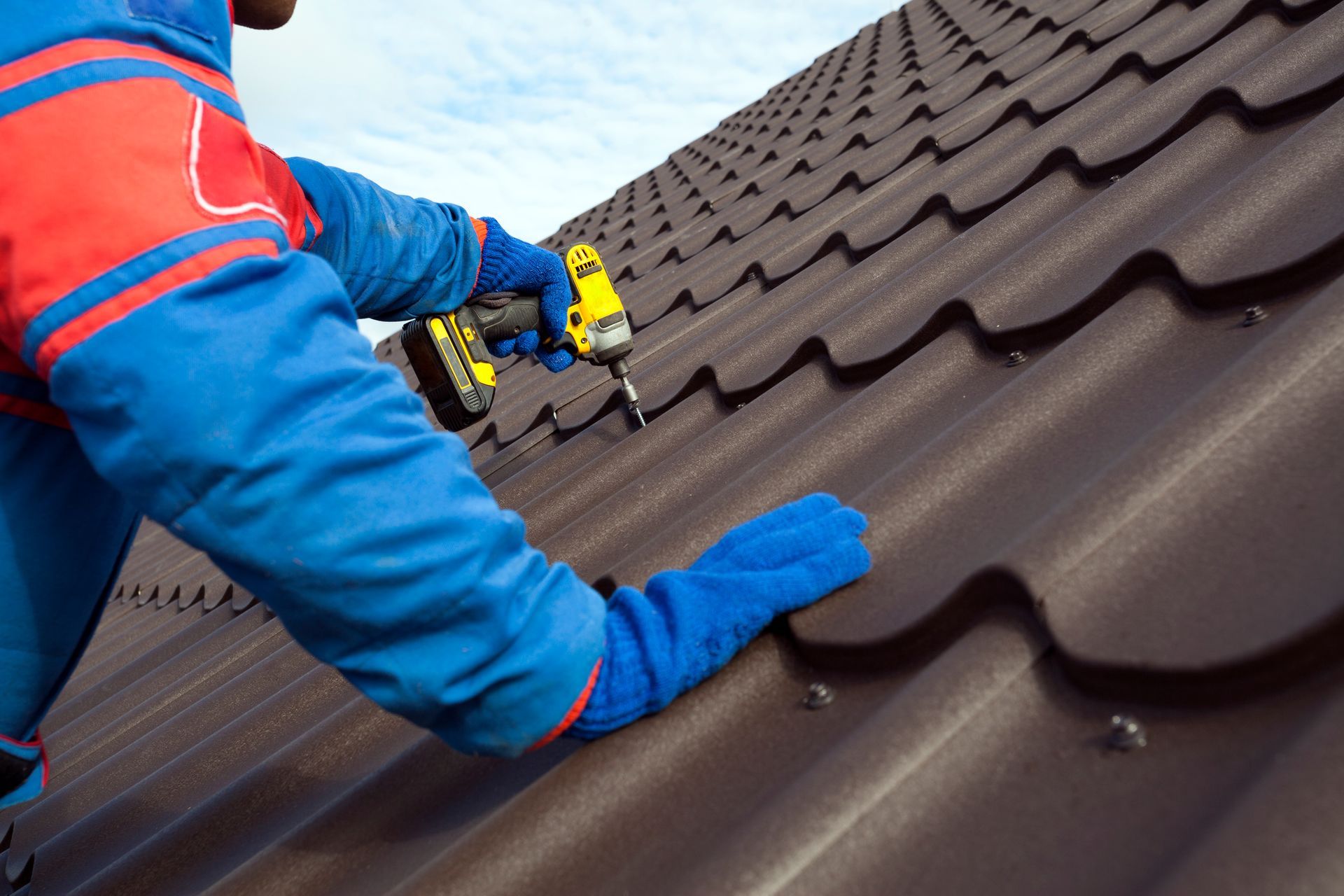 A man is working on a roof with a drill.