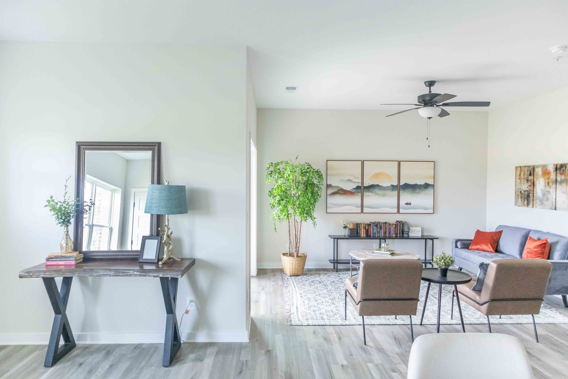 A living room with a couch , chairs , a table , a mirror and a ceiling fan at Riverstone.