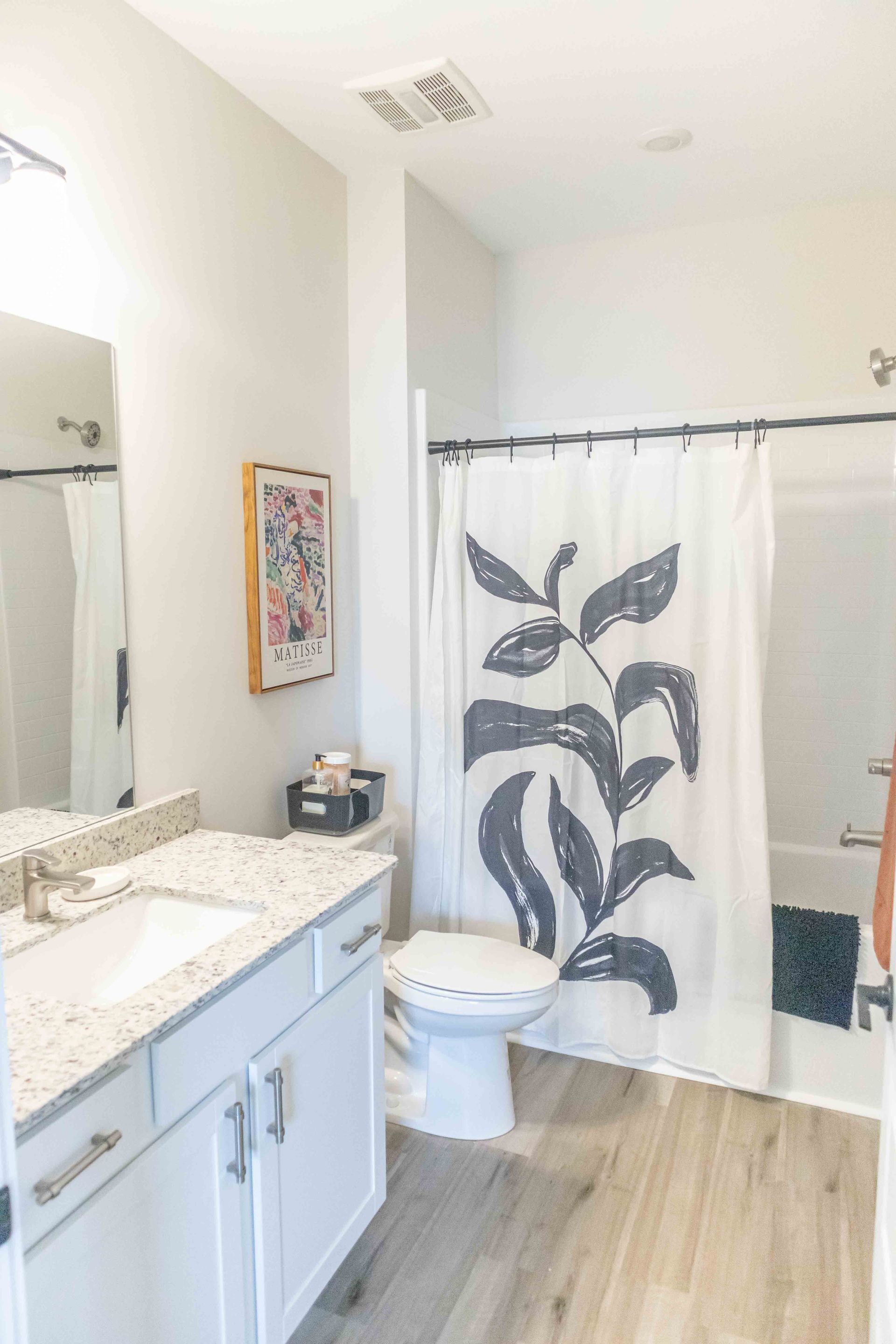 A bathroom with a toilet , sink , and shower curtain at Riverstone.