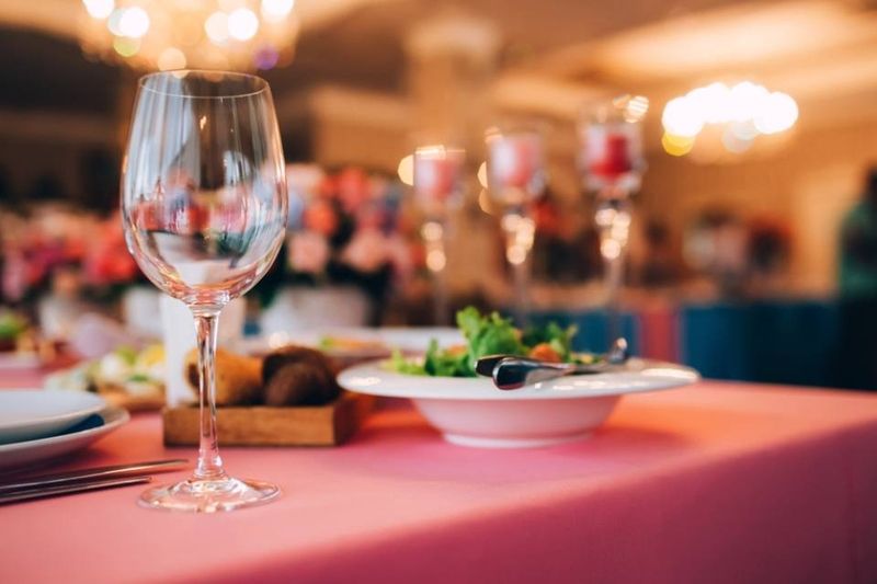 A wine glass is sitting on a table next to a plate of food.