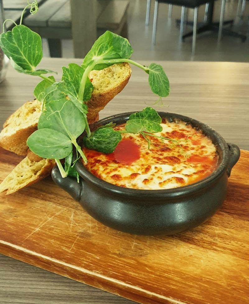 A bowl of food is sitting on a wooden cutting board.