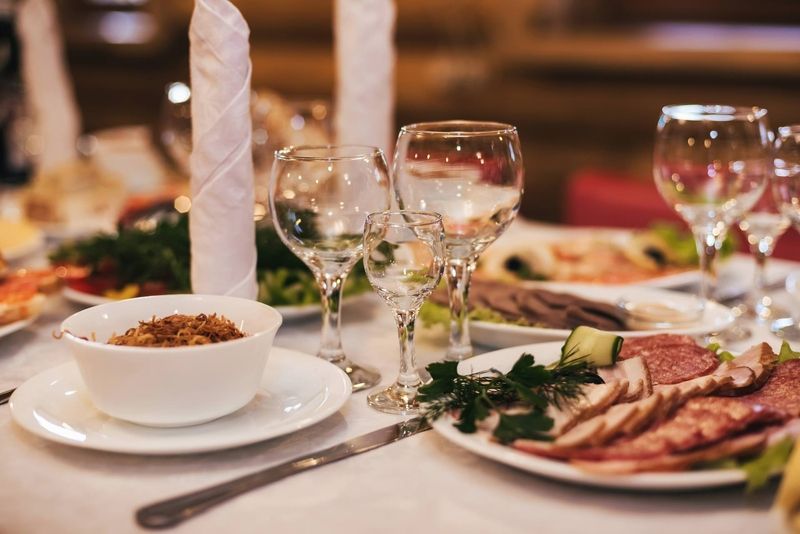 A table with plates of food and wine glasses on it.