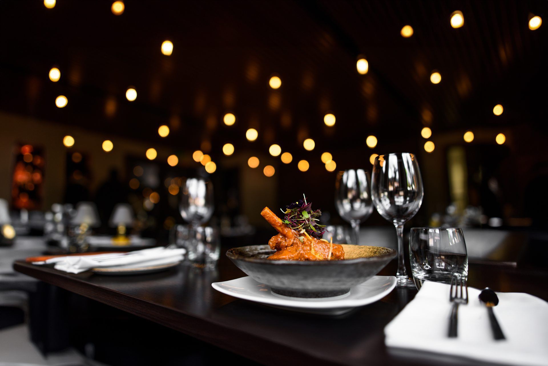 A plate of food and wine glasses on a table in a restaurant.