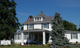 A large white house with a gray roof and a flag on top of it.