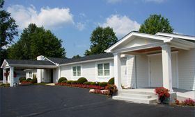 A white house with a black roof and a black driveway