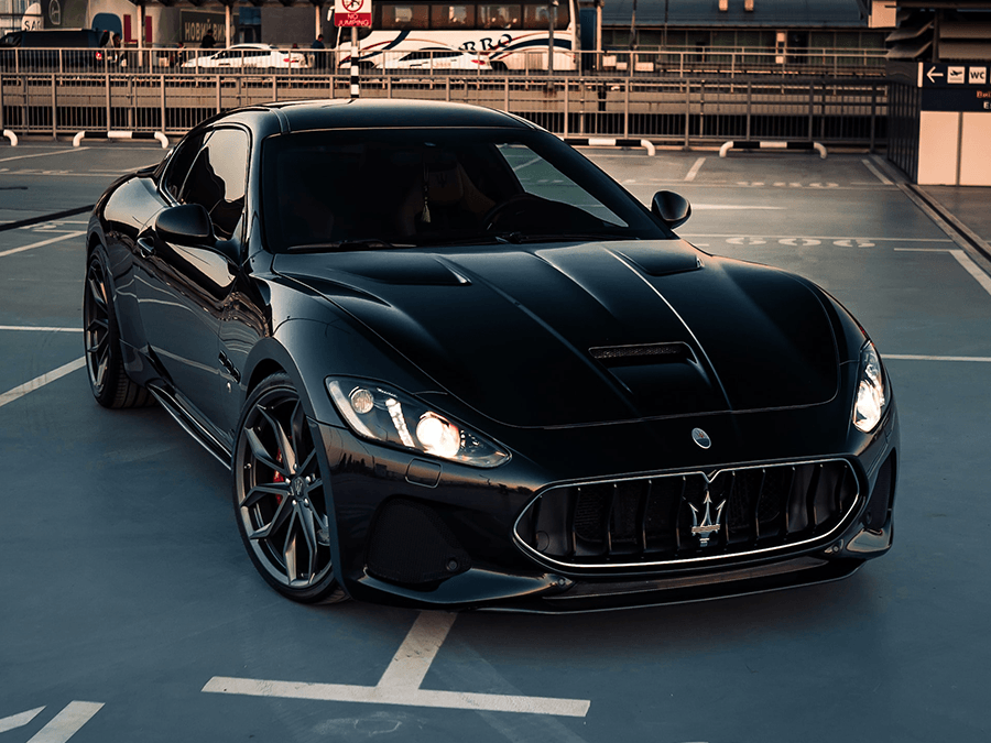 A black maserati granturismo is parked in a parking lot.