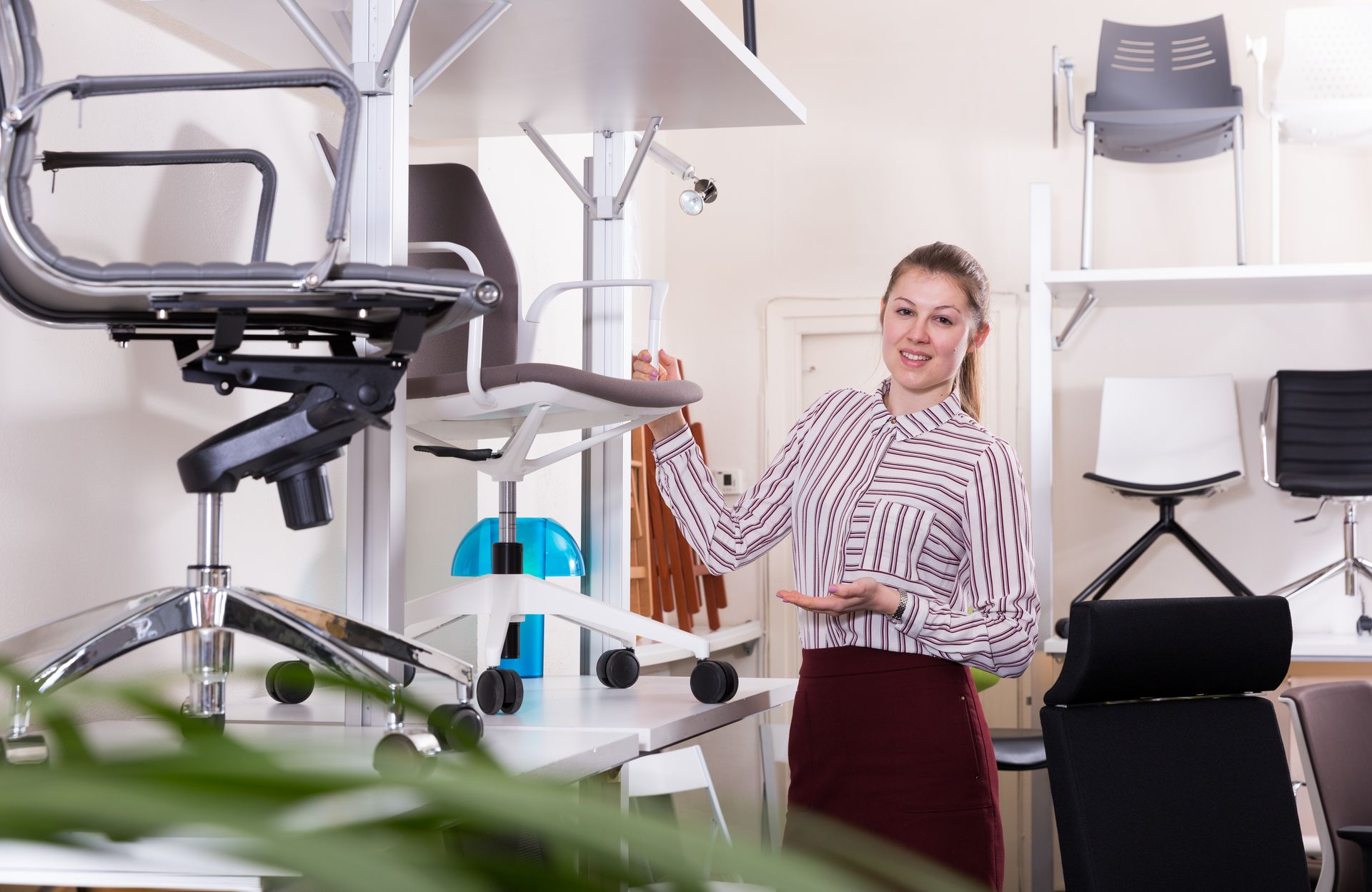 A person in a furniture showroom highlighting an ergonomic office chair. A person in a furniture showroom highlighting an ergonomic office chair.