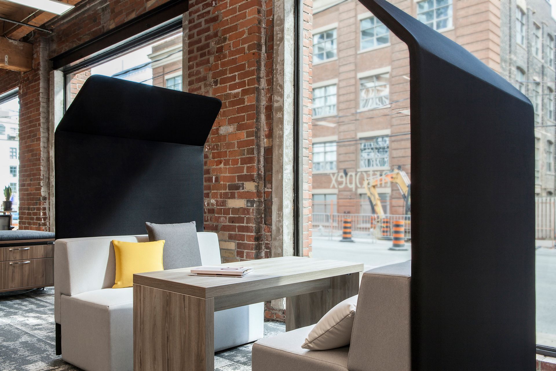 Office space with booth seating, table, and black privacy screens.  View of exterior buildings.