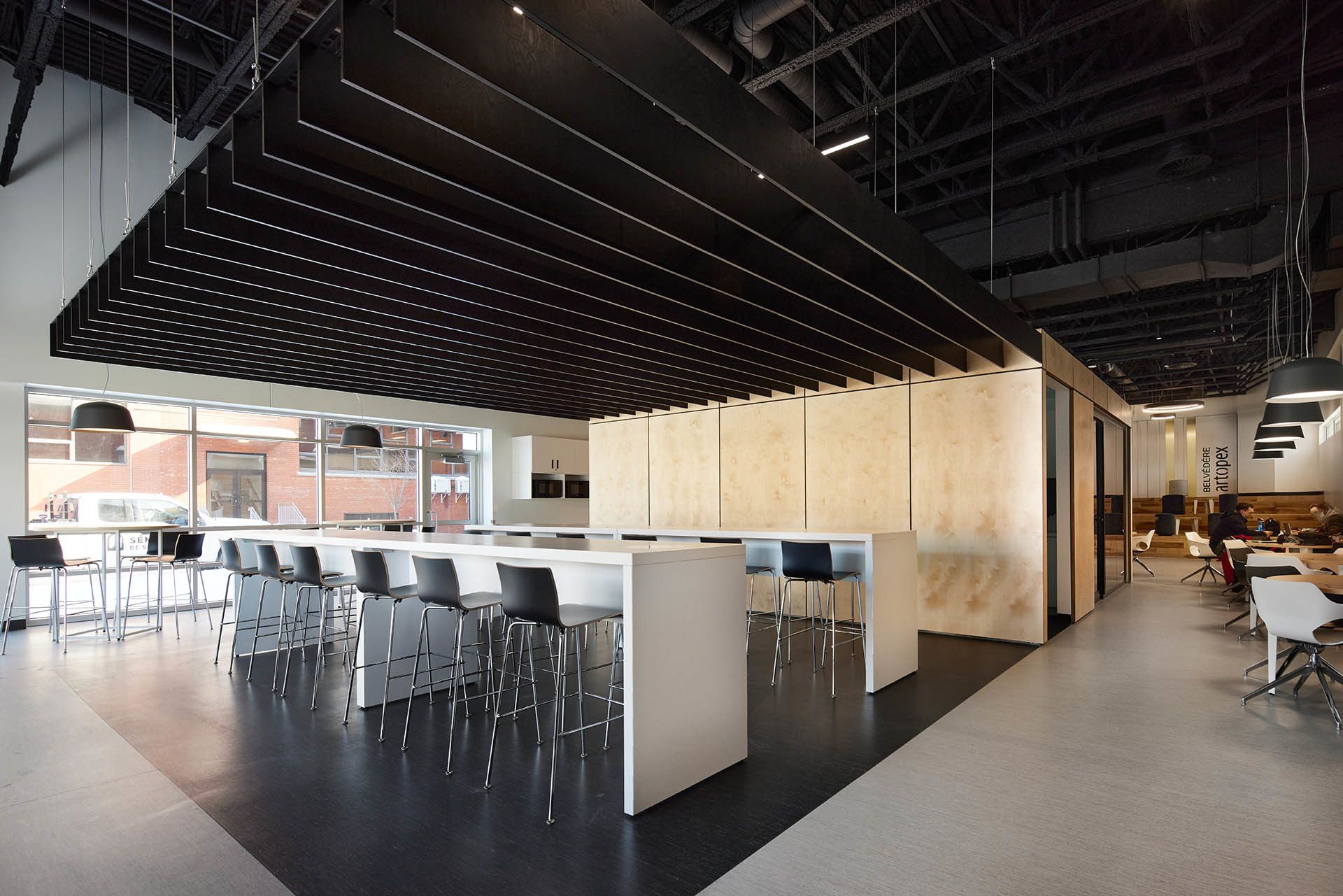 Modern office space with high ceilings, black and white decor, and a large communal table.