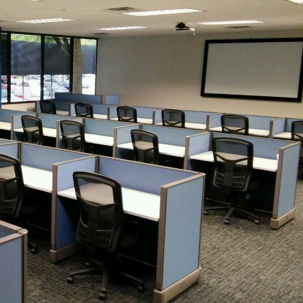 Empty classroom with individual work stations and a projection screen.