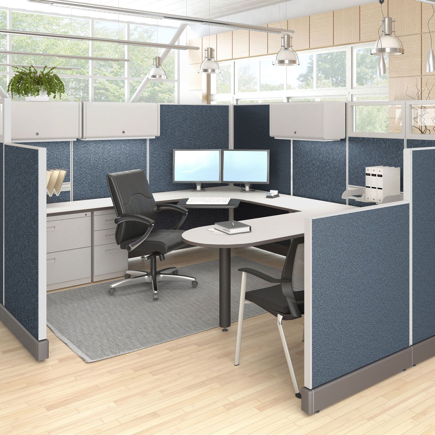 Office cubicle with blue fabric panels, computer monitors, and office chair.