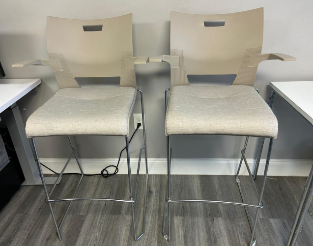 Two beige bar stools with chrome legs in a room.