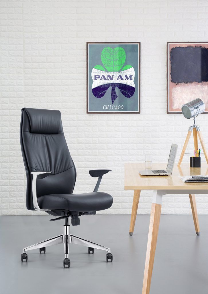 Black office chair, Pan Am poster, laptop, and desk in a modern office setting.
