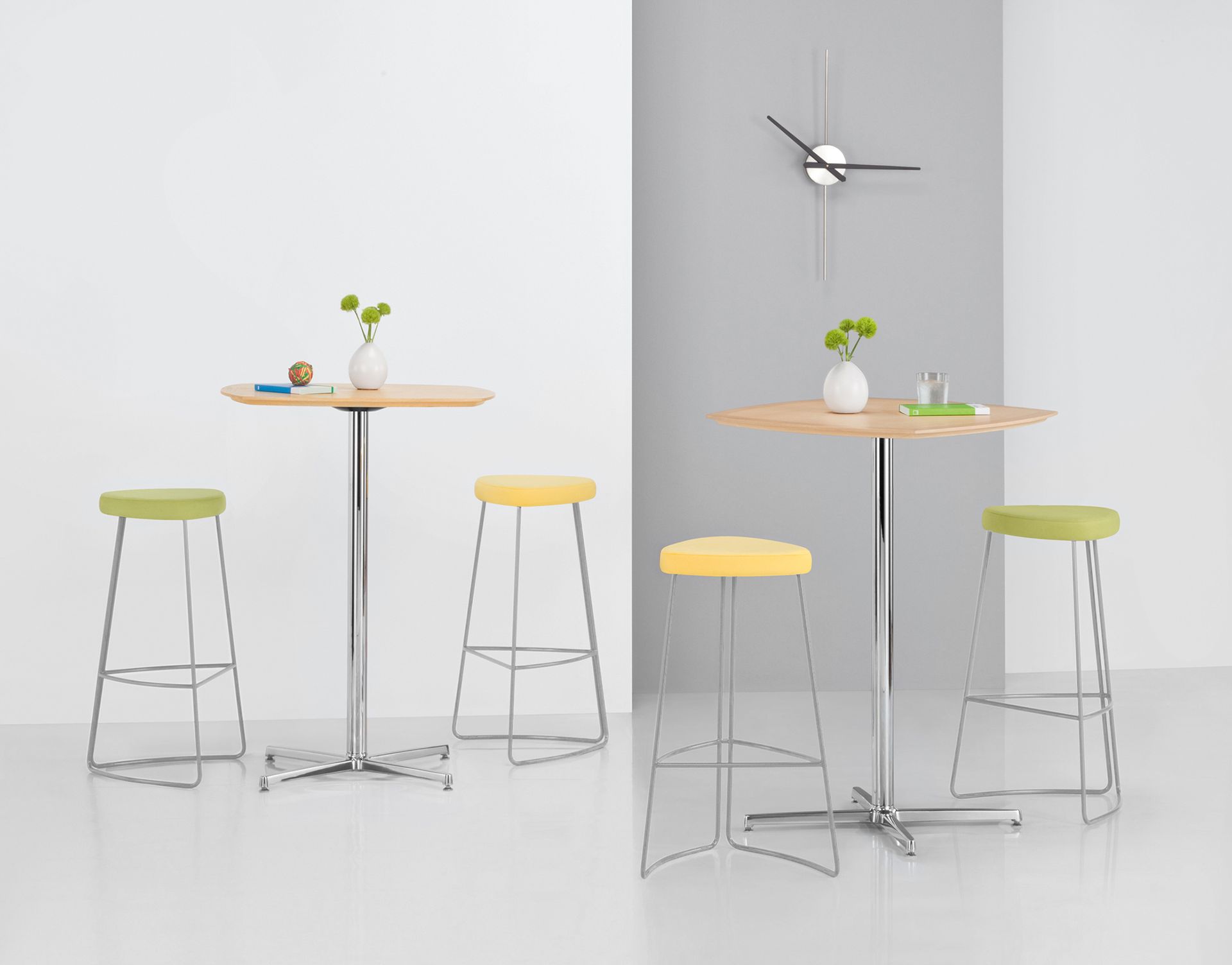 Two sets of high tables with stools, light wood tops, chrome legs, and colorful seats.