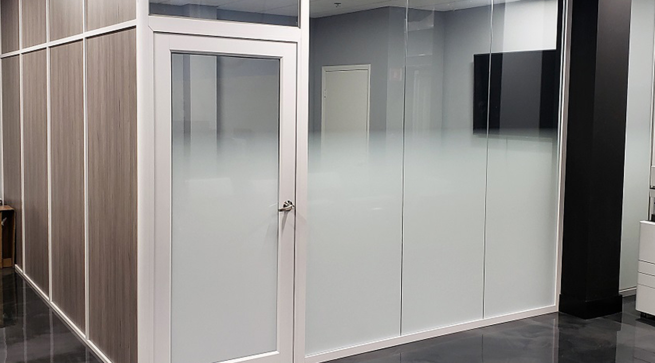 Office space with frosted glass walls and door, wood paneling, and a dark floor.