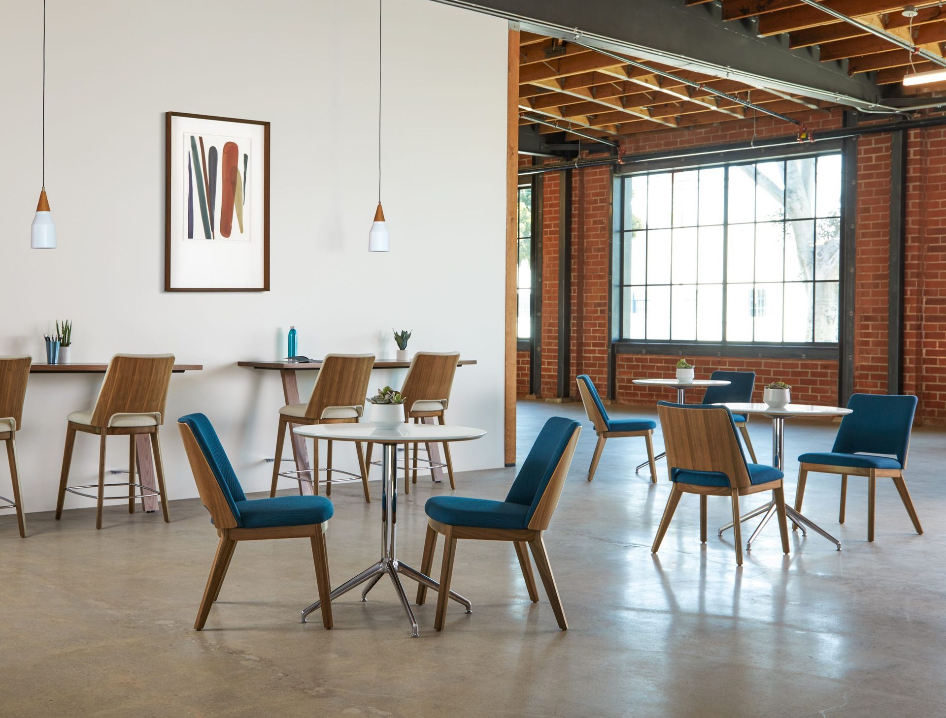 A modern cafe with tables and chairs; teal seating, wood accents, brick wall, and large windows.